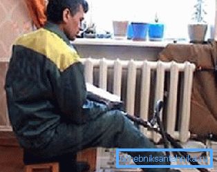 Na fotografii inštalatér umýva radiátory v byte Na fotografii inštalatér umýva radiátory v byte